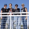 Four students stand smiling with one holding a trophy