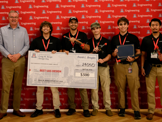 Capstone team 24050 poses with a large check at Design Day 2024. 