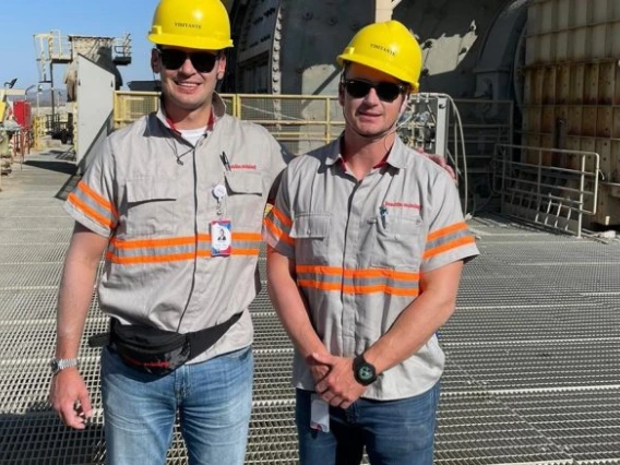 Adam and Jack Lundin are wearing hard hats and posing at a mining site