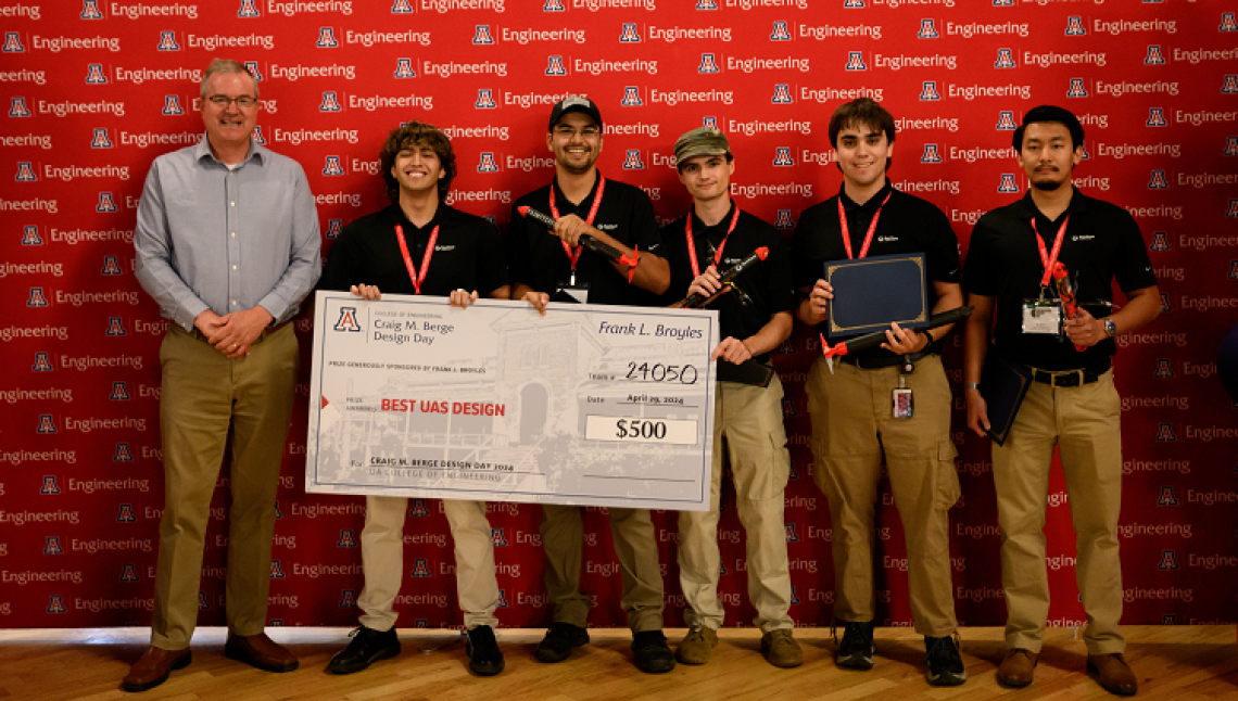 Capstone team 24050 poses with a large check at Design Day 2024. 