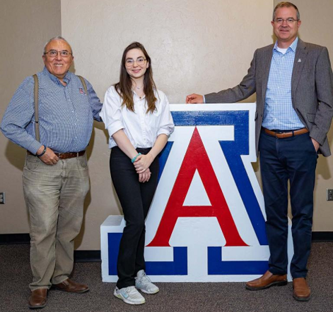 three people standing next to UA block A logo