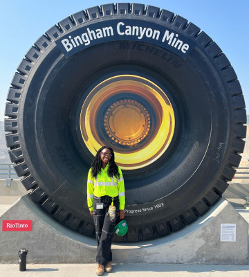 Person standing in front of a large landmark, shaped link a tire