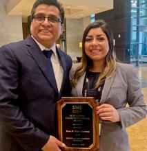 A woman and a man both holding a plaque naming Rosa Maria Rojas the SME Outstanding Young Professional for 2019