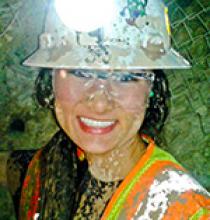 Alyssa Hom in hardhat and safety vest, covered in mud