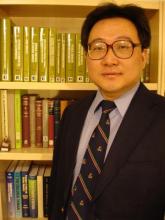 Jinhong Zhang standing in front of a bookshelf