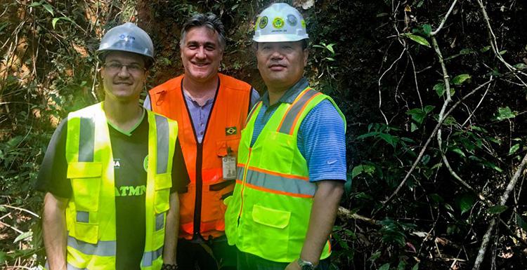 Jaeheon Lee in hard hat and reflective safety vest at a CSN Mining site in Brazil with site geologists Moises Avila and Roberto Virga.