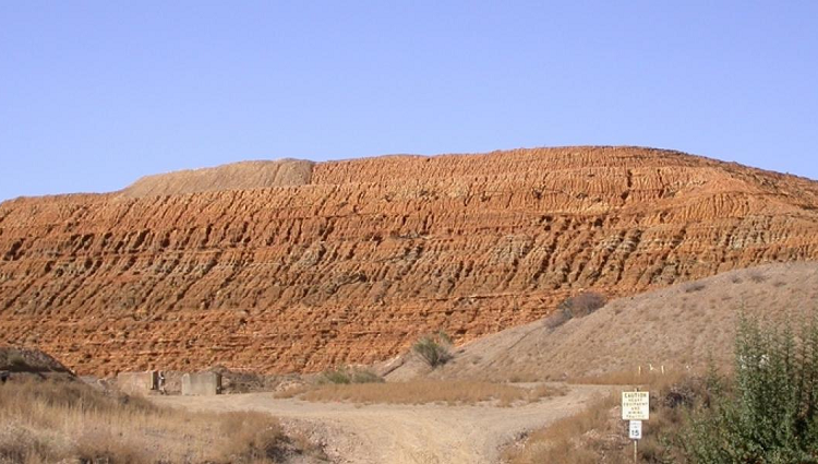 A mine tailings pile (which looks like a large pile of desert) against a blue sky.
