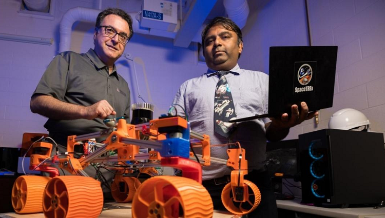 Jekan Thanga and Moe Momayez in a lab with a 3D-printed robot, which is orange and has four wheels